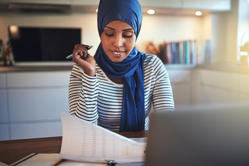 Wall Mural - Young Arabic entrepreneur reading documents while sitting in her