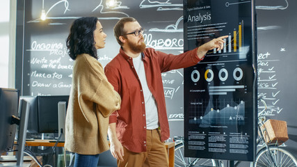 female developer and male statistician use interactive whiteboard presentation touchscreen to look a