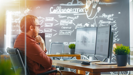 Wall Mural - male mobile video game application developer works on a personal computer, designing wireframe, he's