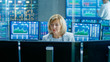 © Gorodenkoff - In the Market Exchange Room Senior Sales Force Representative Works at Her Workstation. In the Background Monitors with Ticker  Numbers, Data and Graphs.