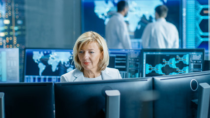 Leinwandbilder - System Monitoring Room Professional Female Operator Observes Correct Functioning of the Facility. In the Background People Working with Interactive Map.