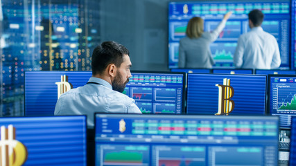 Poster - Stock Market Display Shows Cryptocurrency and It's Market Value. People In the Background Working Selling and Buying Bonds.