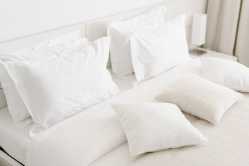 comfortable soft pillows on the bed. close-up white bedding sheets and pillow on light wall room bac