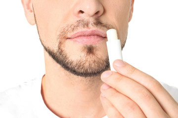 Wall Mural - Man applying hygienic lip balm, on white background