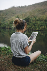 Wall Mural - Woman alone in nature listening to music with headphones and digital tablet music and relaxation concept