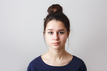 Portrait Of A Pimply Teenage Girl In A Blue T-shirt On A Gray Background, Sad Doubting Face