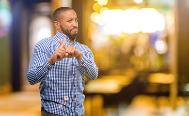 Canvas Print - African american man with beard annoyed with bad attitude making stop sign with hand, saying no, expressing security, defense or restriction, maybe pushing at night