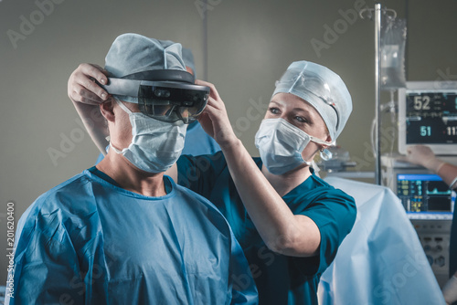 Fotografía Nurse assisting surgeon with mounting augmented reality holographic hololens gla