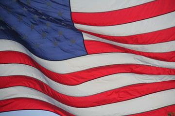 American Flag Stars and Stripes Waving Backlit by the Afternoon Sun Against a Clear Blue Sky