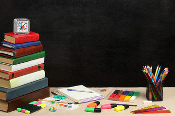 School theme with books with colors plasticine and watch black background