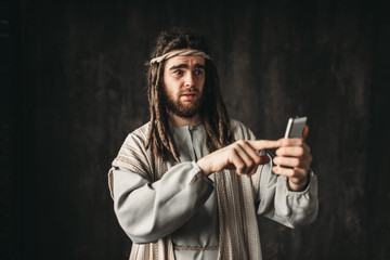 Wall Mural - Man in the image of Jesus Christ holds phone