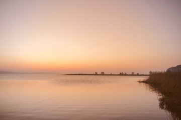 Wall Mural - sunrise by a lake with silhouettes