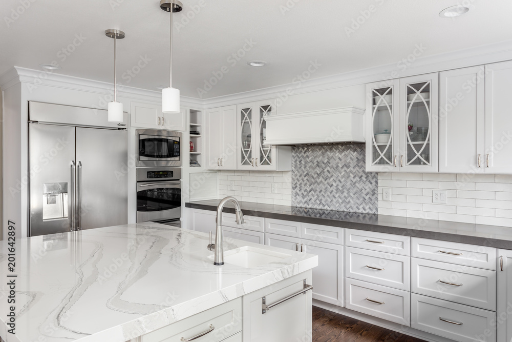 Kitchen in New Luxury Home with White Cabinets, Stainless Steel Appliances, and Large Island with Sink - obrazy, fototapety, plakaty 