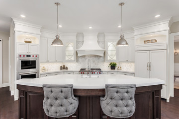 Kitchen in new luxury home: large, elegant kitchen, with pendant lights, and huge island, with refrigerator and double ovens. 