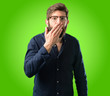 © Krakenimages.com - Young hipster man with big beard covers mouth in shock, looks shy, expressing silence and mistake concepts, scared over green background