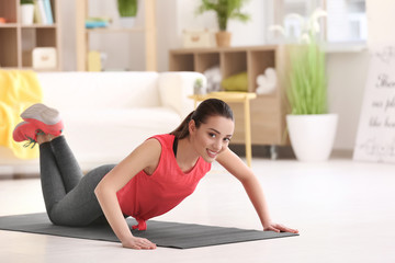 Wall Mural - Beautiful young woman doing fitness exercise at home