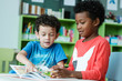 © mangpor2004 - American and African boys are reading together with happiness in their kindergarten classroom, kid education and diversity concept