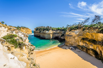 Bright sunny summer coast view to a beautiful sandy beach bay and rocky erosion sand limestone cliff of Great Ocean Road, walking at Loch Ard Gorge, Port Campbell National Park, Victoria/ Australia