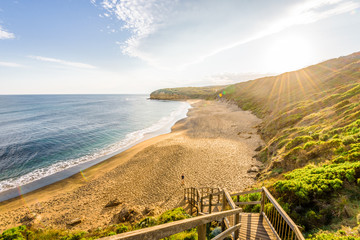 Bright sunny summer sunset sunrise coast view to wild Bass Strait sea, stairs lead you to empty sandy beach bay at Great Ocean Road, Torquay, best surfing relaxing, Australia