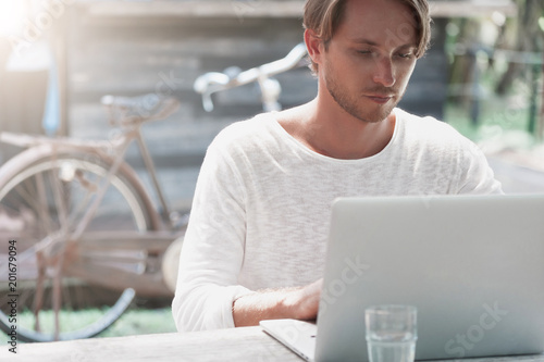 Cuadros en Lienzo Young male freelancer sitting in cafe working in laptop
