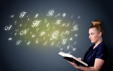 Wall Mural - Casual young woman holding book with shiny letters flying out of it