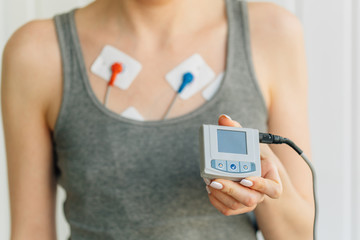 Woman wearing holter monitor device for daily monitoring of an electrocardiogram. Treatment of heart diseases