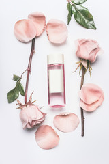 Wall Mural - pink cosmetic bottle with facial roses water or toner with essential oil , flowers and petals on whi