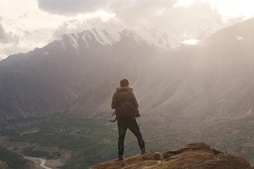 Wall Mural - traveller with backpack standing on mountain peak, enjoying beautiful sunset and valley view. travel