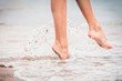 girl comes barefoot into the water in the summer at sea