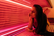 a young long-haired girl lies in a horizontal solarium, sunbathing under ultraviolet rays
