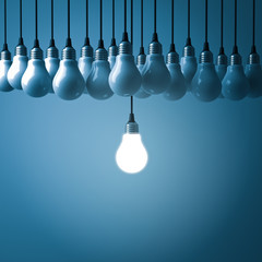 Fototapete - Stand out from the crowd and different creative idea concepts , One hanging light bulb glowing with unlit incandescent bulbs on dark blue background , 3D rendering.
