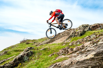 Wall Mural - Cyclist in Red Jacket Riding Mountain Bike Down Rocky Hill. Extreme Sport and Adventure Concept.