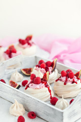 Delicious mini Pavlova meringue cake decorated with fresh raspberry, figs  and berry sauce