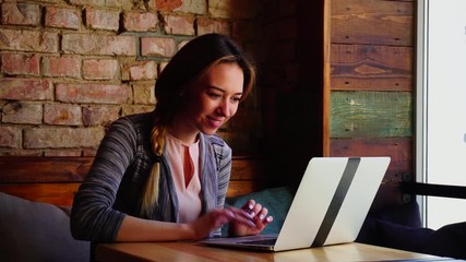 Wall Mural - Beautiful woman gets acquainted with handsome man by Internet using laptop at cafe. Concept of dating websites and resting with modern gadget. Young female person sitting on sofa with pillows has