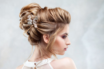 Young beautiful bride with an elegant high hairdo. Wedding hairstyle with the accessory in her hair