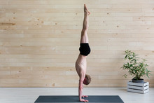 Sporty Man Practices Yoga Handstand Asana Adho Mukha Vrikshasana At The Yoga Studio. Balance Exercise