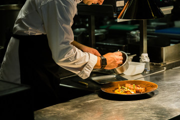 Chef plating dish on kitchen counter while recording at kitchen hotel.