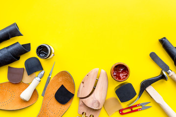 Wall Mural - Clobber tools. Hummer, awl, knife, sciccors, wooden shoe, paint and leather. Yellow background top view space for text