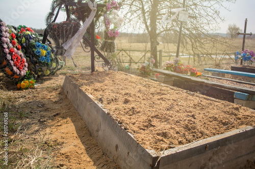 Fotografie, Obraz photo of a fresh grave, which is ennobled by a graveyard worker