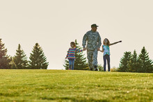 Soldier And His Daughters On The Grass. Happy Family On The Lawn, US Army Soldier And His Little Daughters At Vacation.