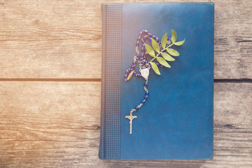 Cross on the antique Bible on a wooden table background. Holy bo