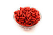 © isuhi - Red capsules filled with medicine, stacked in a glass cup on a white background.