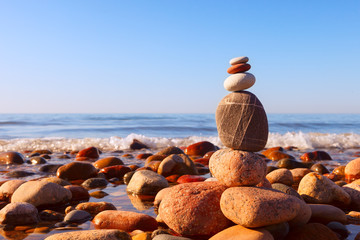 Wall Mural - Pyramid of multicolored pebbles on a background of the summer sea.