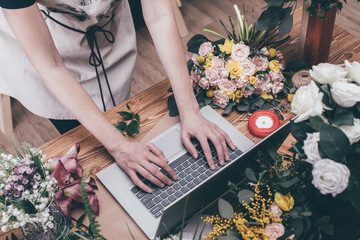 Poster - Florist working in modern flower shop on laptop . Young woman entrepreneur with her own business.