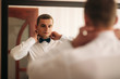 © Aleksandr - The groom is dressed at home in a suit. Cute groom posing for a photographer