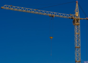 Yellow construction tower crane against blue sky