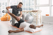© zinkevych - Special training. Pleasant young man doing rehabilitation exercises while being in the gym