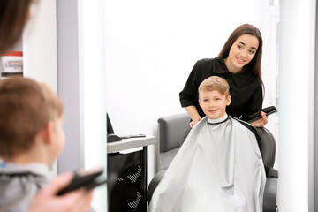 Wall Mural - Professional female hairdresser working with little boy in salon