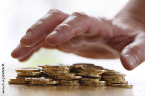 Fotografía Love of money - Greedy hand grabbing or reaching out for pile of golden coins
