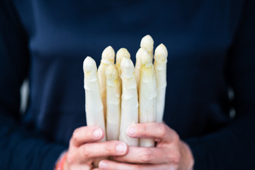 Weißer frischer Spargel in der Hand gehalten von einer jungen Frau zum schälen und kochen